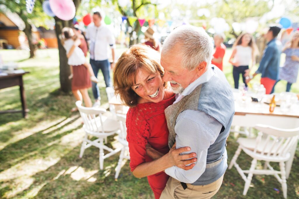 A senior couple dancing on a garden party outside in the backyard.
